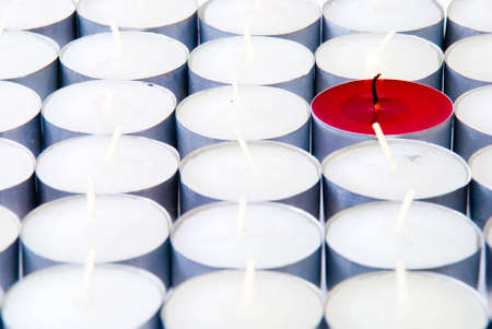 One red candle among lots of white candlesの写真素材
