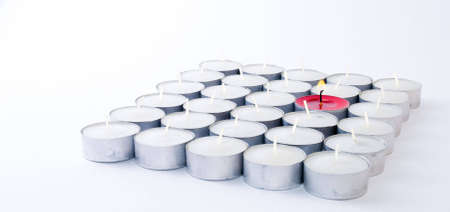 One red candle among lots of white candles, symbolizing originality, uniqueness, openness of mind, and also good ideas springing out from teamwork.の写真素材