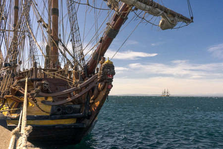Very old sailboat with multiple masts from 1703 tied to the shore with a rope and another wooden ship in the backgroundの写真素材