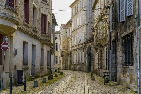 View of a cobblestone street with old buildings in Angouleme, France. The buildings look worn but dreamy and beautiful.の写真素材