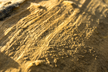 Closeup of pattern in sand with the sun before setting resulting in long shadows and a rich texture.