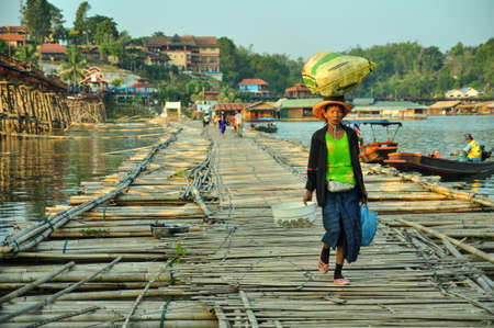 Villager move things by her head in Sangklaburi, Karnjanaburi province, Thailandのeditorial素材