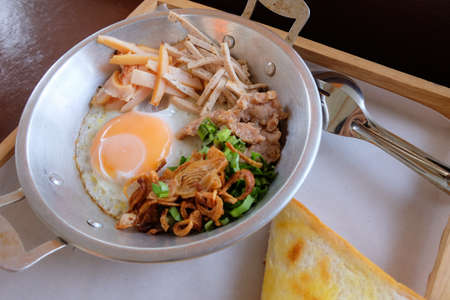Egg pan with pork, fried garlic and breadの写真素材