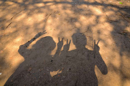 Shadow of two people make the v-sign shape by their fingersの写真素材