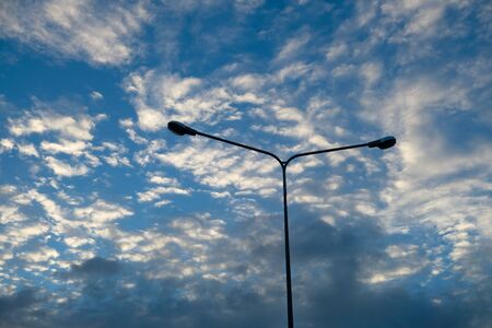 Blue sky background with clouds and silhouette of electric poleの写真素材