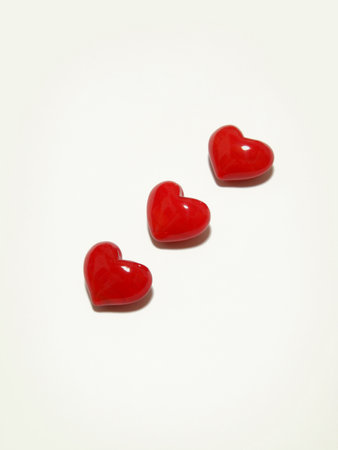 Three three-dimensional glossy red hearts lined up diagonally.の写真素材