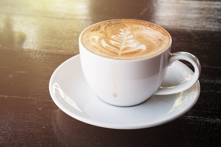 Hot coffee with latte art on wooden table at cafeの写真素材