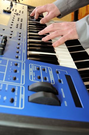 Man's hands playing the keyboard of a synthesizer
