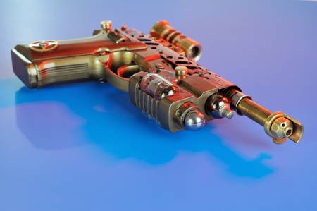 Steampunk style future pistol. On a dark blue backgroundの写真素材
