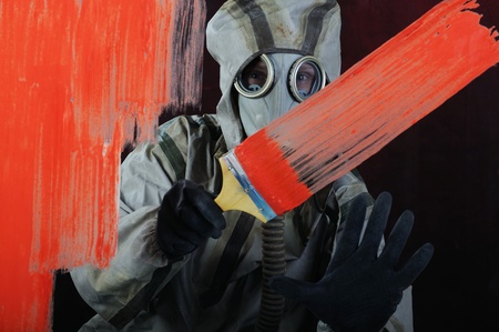 The person in a gas mask paints over glass a red paintの写真素材
