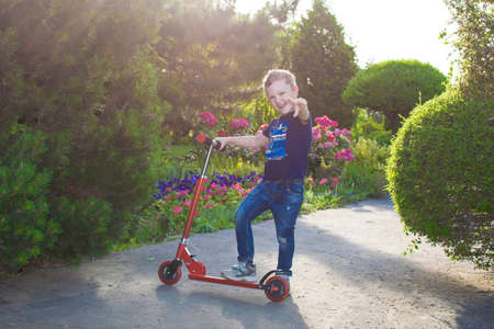 Boy playing on his scooter in the local park.