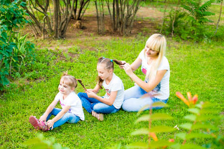 Young mother and two daughters playing in grassの写真素材