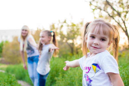 Young mother and two daughters playing in grassの写真素材