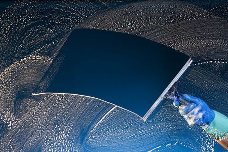 A soapy window with a squeegee cleanjng the glass