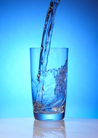 Spring water is poured into crystal drinking glassの写真素材