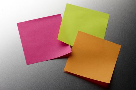 Three colorful blank stickie notes tacked to metal backgroundの写真素材