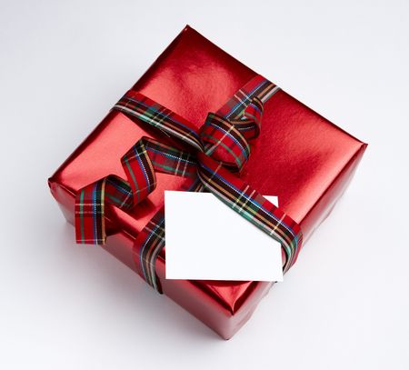 Christmas wrapping and ribbon on box with blank white card shot on white background with soft shadow