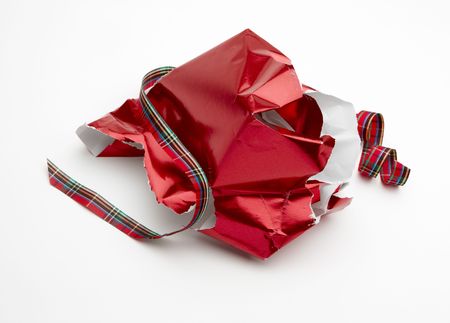 torn Christmas gift wrapper and ribbon shot on white background with soft shadow and room for copyの写真素材