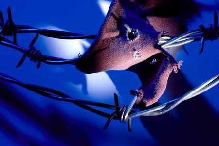 Piece of shirt caught on barbed wire fence at nightの写真素材