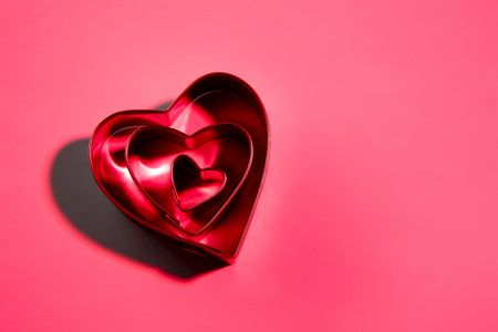 Arrangement of 3 heart shaped cookie cutters shot with red glow and space for copyの写真素材