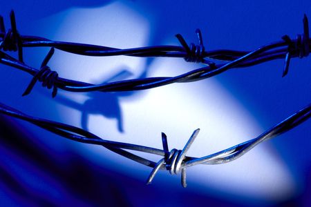 Barber wire shot at night with searchlight casting shadowsの写真素材