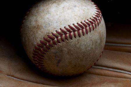 Close up shot of well worn baseball sitting in baseball gloveの写真素材