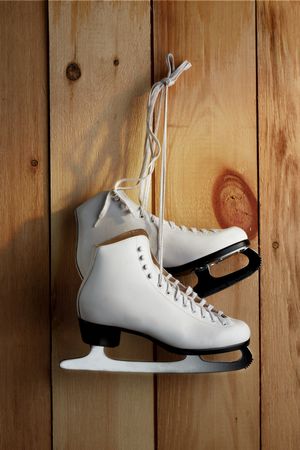 Pair of woman's figure skates hanging inside barn with morning sun streaming inの写真素材