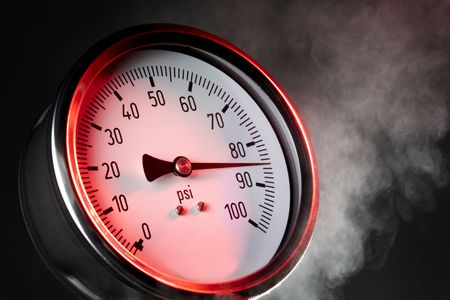 pressure gauge under extreme stress with steam and red warning light