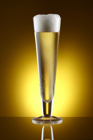 Beer shot in Pilsner glass with amber background and space for copyの写真素材