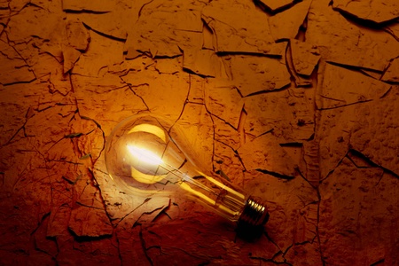 Closeup of Illuminated light bulb on parched red desert surfaceの写真素材
