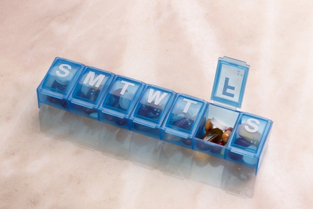 Blue plastic pill organizer shot on marble table with space for copy
