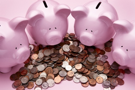 4 pink piggy banks feasting on a pile of coinsの写真素材