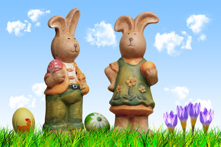 two easter bunny dolls, arranged with grass sky, clouds, eggs and crocuses