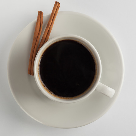 White coffee cup with a cinnamon sticks on a platterの写真素材