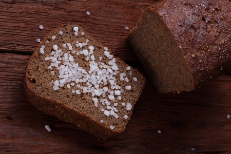 Organic homemade bread with sea salt presented in center on wooden rustic background Close focused top viewの写真素材