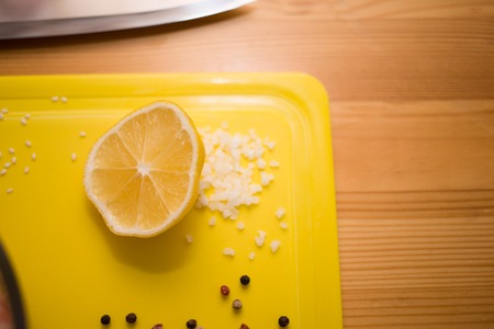 Lemon, salt and pepper on cutting boardの写真素材