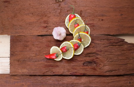 Red chili pepper, slices a lemon, garlic on brown cutting board.の写真素材
