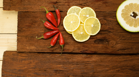Red chili pepper, slices a lemon on brown cutting board.の写真素材