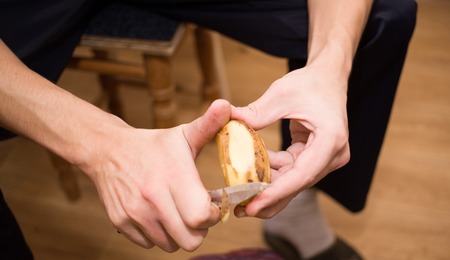 Mens Hands peeling potatoes in kitchen, closeupの写真素材
