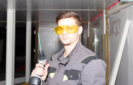 Young engineer in goggles with cordless screwdriverの写真素材