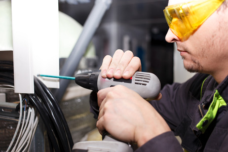 Young engineer in goggles with cordless screwdriver