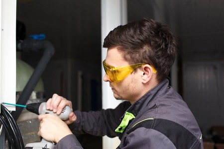 Young engineer in goggles with cordless screwdriver
