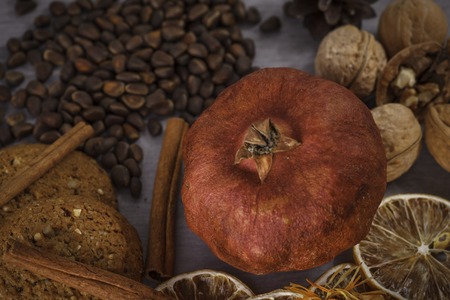 Pomegranate, surrounded by autumn gifts. Slices of lemon and pine nuts in a vaseの写真素材
