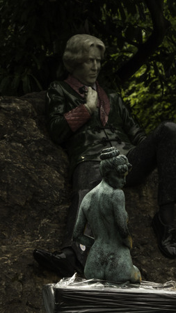 Statue of naked women in view of statue of Oscar Wildeのeditorial素材