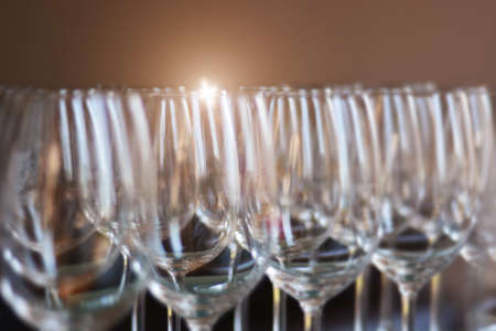 Wine glasses shallow focus blurred foreground defocused background bokeh light optical refraction sun reflection flares.の写真素材