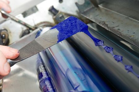 Applying cyan ink on the die cutter of a printing press with a filling knifeの写真素材