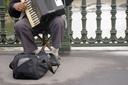 A street musician playing the accordion on one of Paris' many bridgesの写真素材