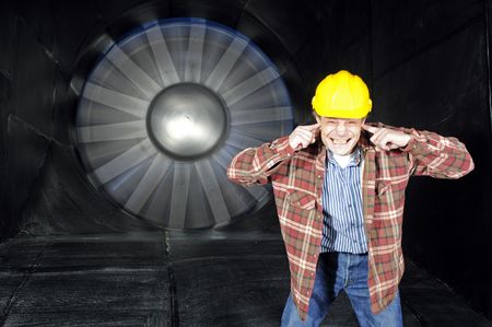 An engineer, covering his ears to protect them from the noise of a wintunnel being testedの写真素材