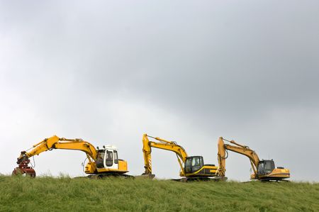 Three diggers, parked on a dyke in Zeeland, the Netherlandsの写真素材