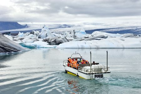 An amphibuous vehicle taking tourists for a cruise around the icebergs in the Jokulsarlon glacier lake, where huge chunks of ice from the Vatnajokull glacier float out to the Atlantic oceanの写真素材